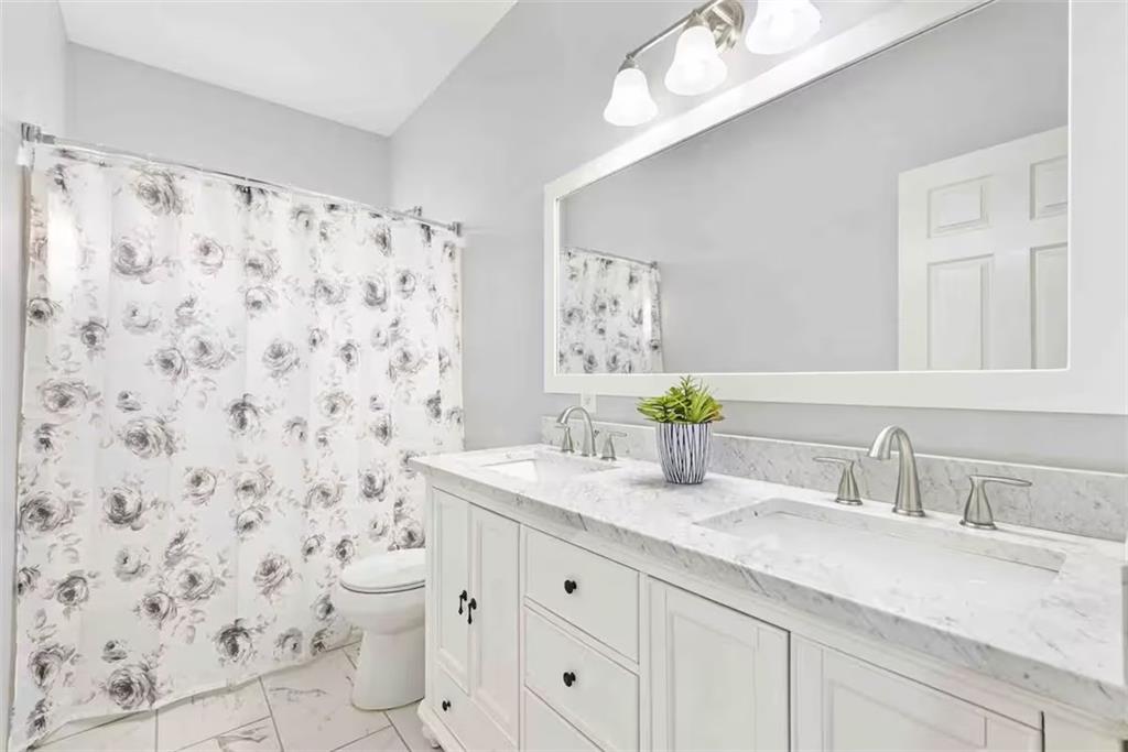 673 Windsor Street Southwest Atlanta, GA 30310 - Photo 24 of 29 a bathroom with a granite countertop sink a toilet and a shower