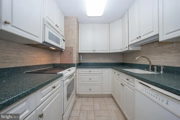 a kitchen with granite countertop white cabinets and white appliances