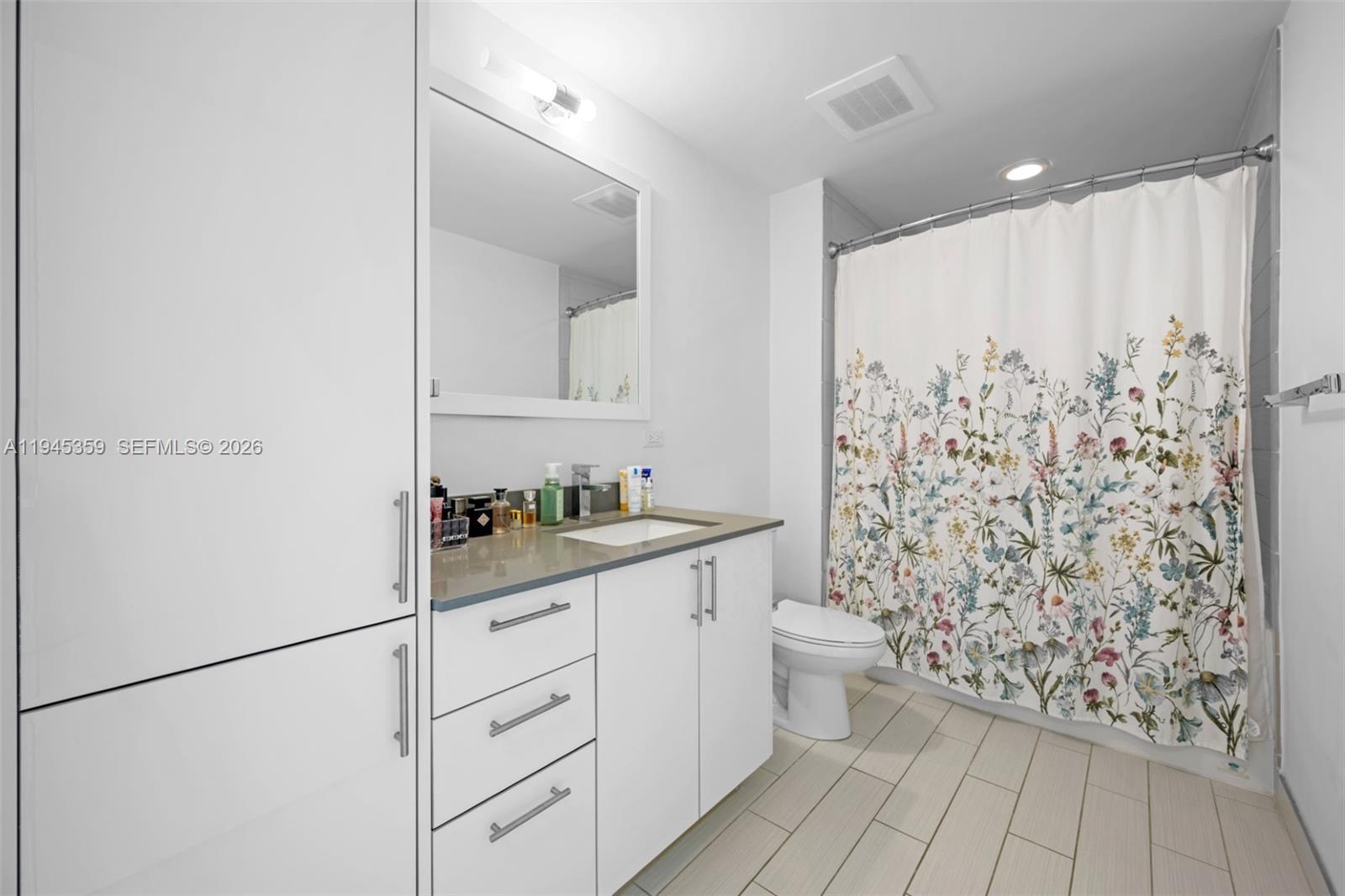 999 Southwest 1st Avenue, Unit 2214 Miami, FL 33130 - Photo 20 of 36 a bathroom with a granite countertop sink a toilet and a shower