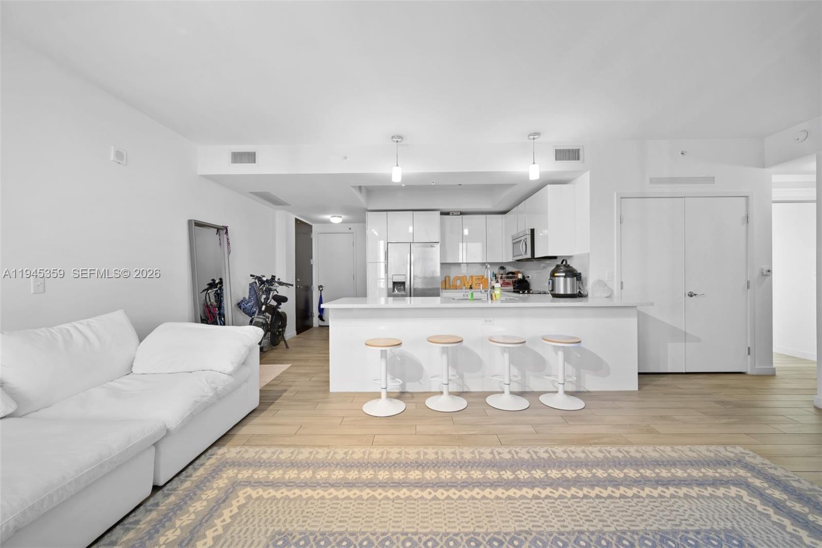 999 Southwest 1st Avenue, Unit 2214 Miami, FL 33130 - Photo 6 of 35 a living room with white couches and kitchen view with wooden floor