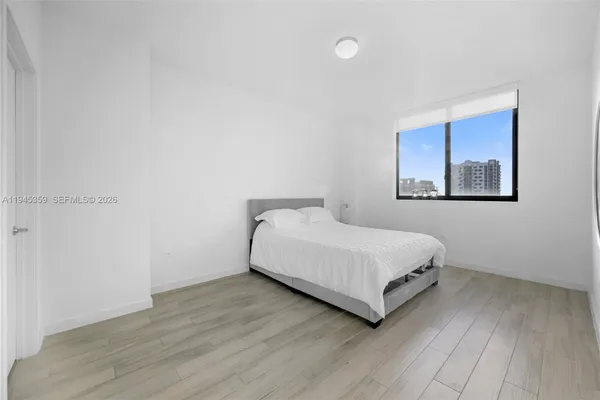 a view of a bedroom with wooden floor and window