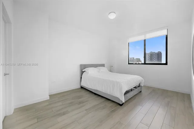 a view of a bedroom with wooden floor and window
