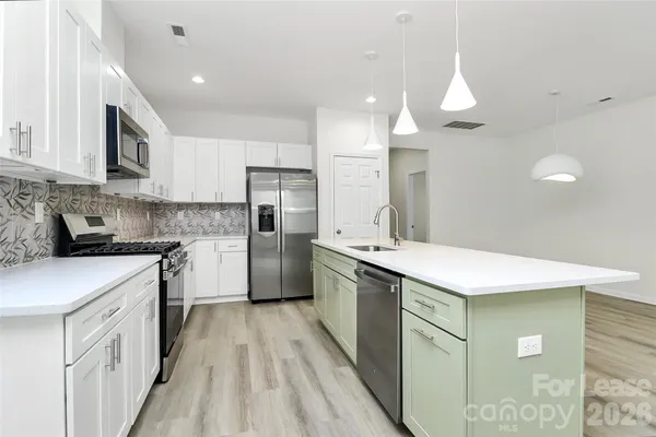 a kitchen with a sink a counter top space stainless steel appliances and cabinets