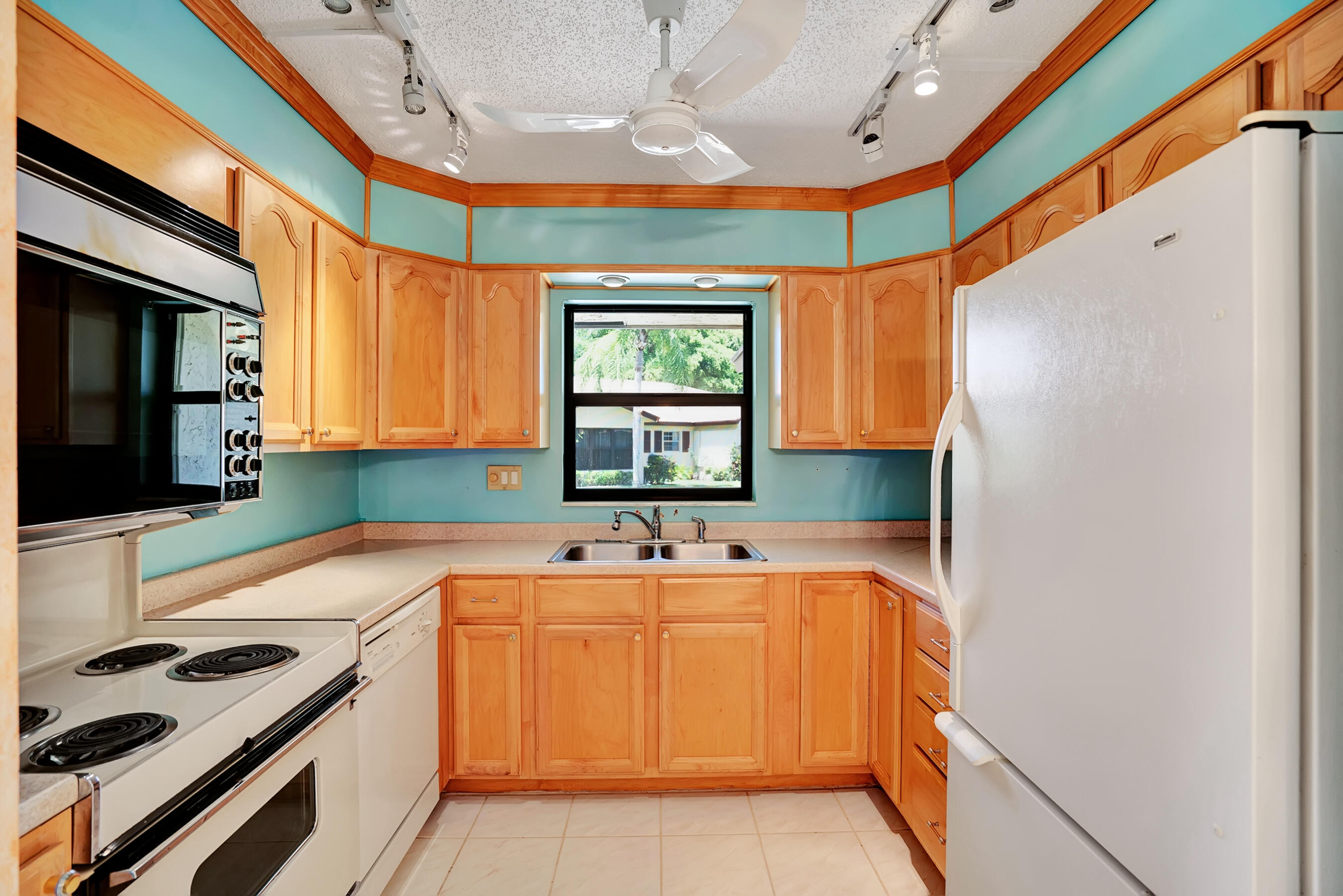 14100 Nesting Way, Unit D Delray Beach, FL 33484 - Photo 13 of 31 a kitchen with a sink a window stainless steel appliances and cabinets