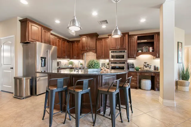 a kitchen with stainless steel appliances kitchen island granite countertop a refrigerator and a stove top oven