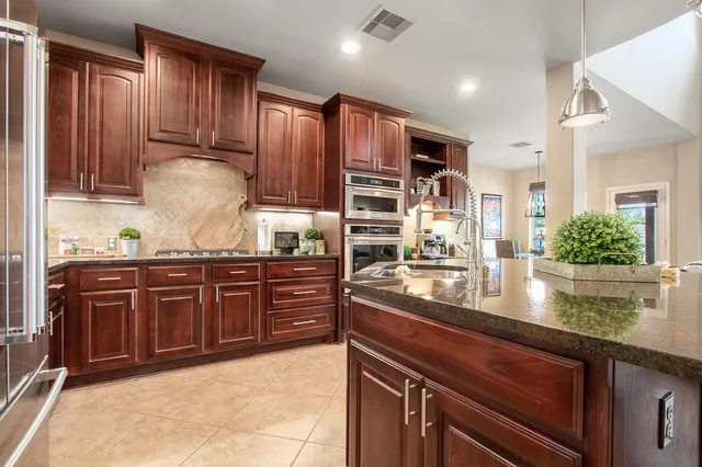 a kitchen with stainless steel appliances granite countertop wooden cabinets a stove top oven and granite counter tops