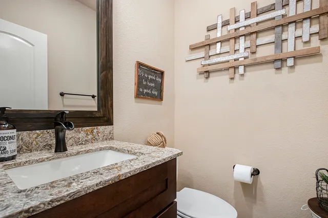 a bathroom with a granite countertop sink a toilet and a mirror