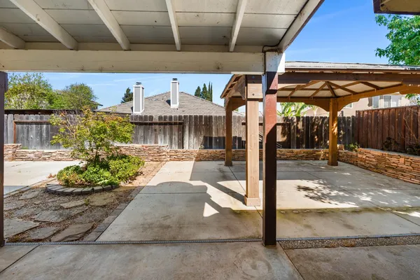 a view of a patio with a table and chairs under an umbrella with a small yard
