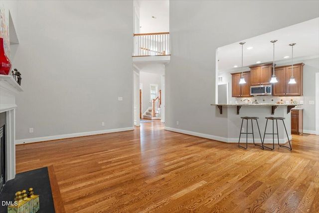 a kitchen with stainless steel appliances kitchen island granite countertop a stove a refrigerator a sink a dining table and chairs with wooden floor