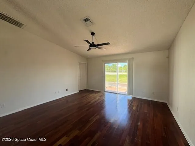 an empty room with wooden floor ceiling fan and windows