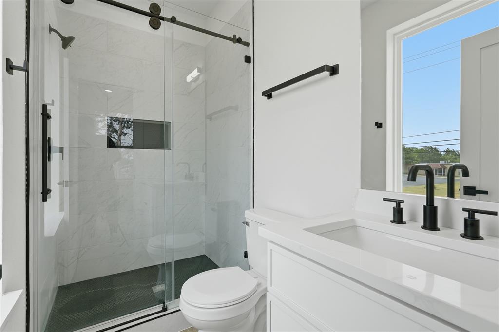 3905 Blue Ridge Boulevard Dallas, TX 75233 - Photo 20 of 25 Glass-enclosed shower with a matte black barn door style frame, tiled shower walls, and a built-in shower niche