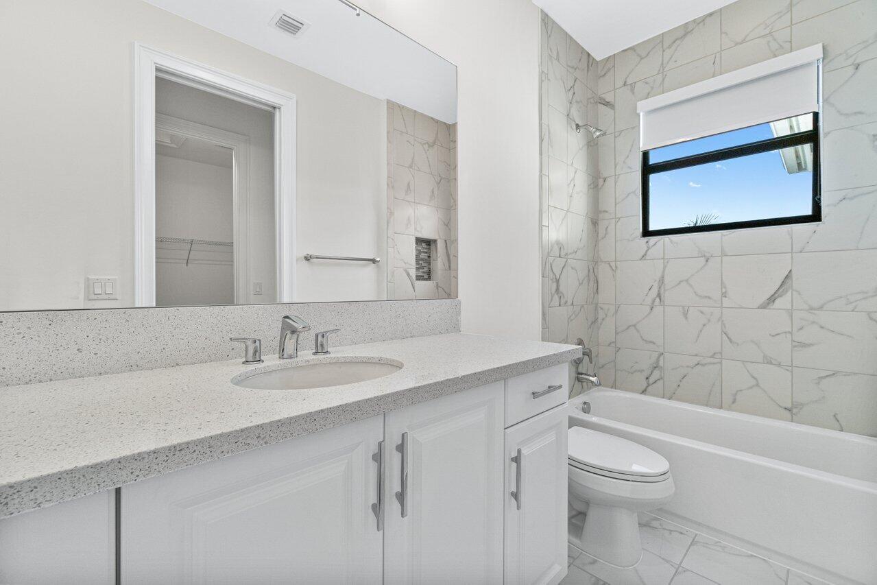 17352 Rosella Road Boca Raton, FL 33496 - Photo 30 of 41 a bathroom with a granite countertop toilet a sink a mirror and a bathtub
