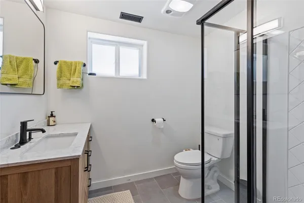 a bathroom with a granite countertop sink a toilet and a mirror