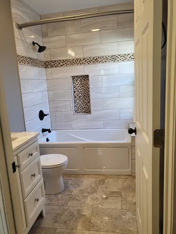 a bathroom with a granite countertop bathtub sink vanity mirror and toilet