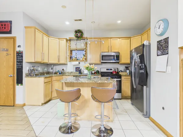 a kitchen with stainless steel appliances granite countertop a refrigerator a stove a sink and a dining table with garden view
