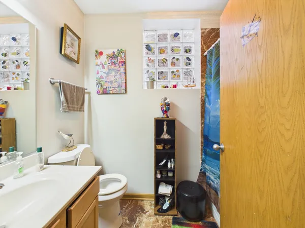 a bathroom with a granite countertop sink and a toilet