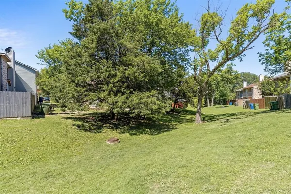 a view of a yard in front of a house with a large tree