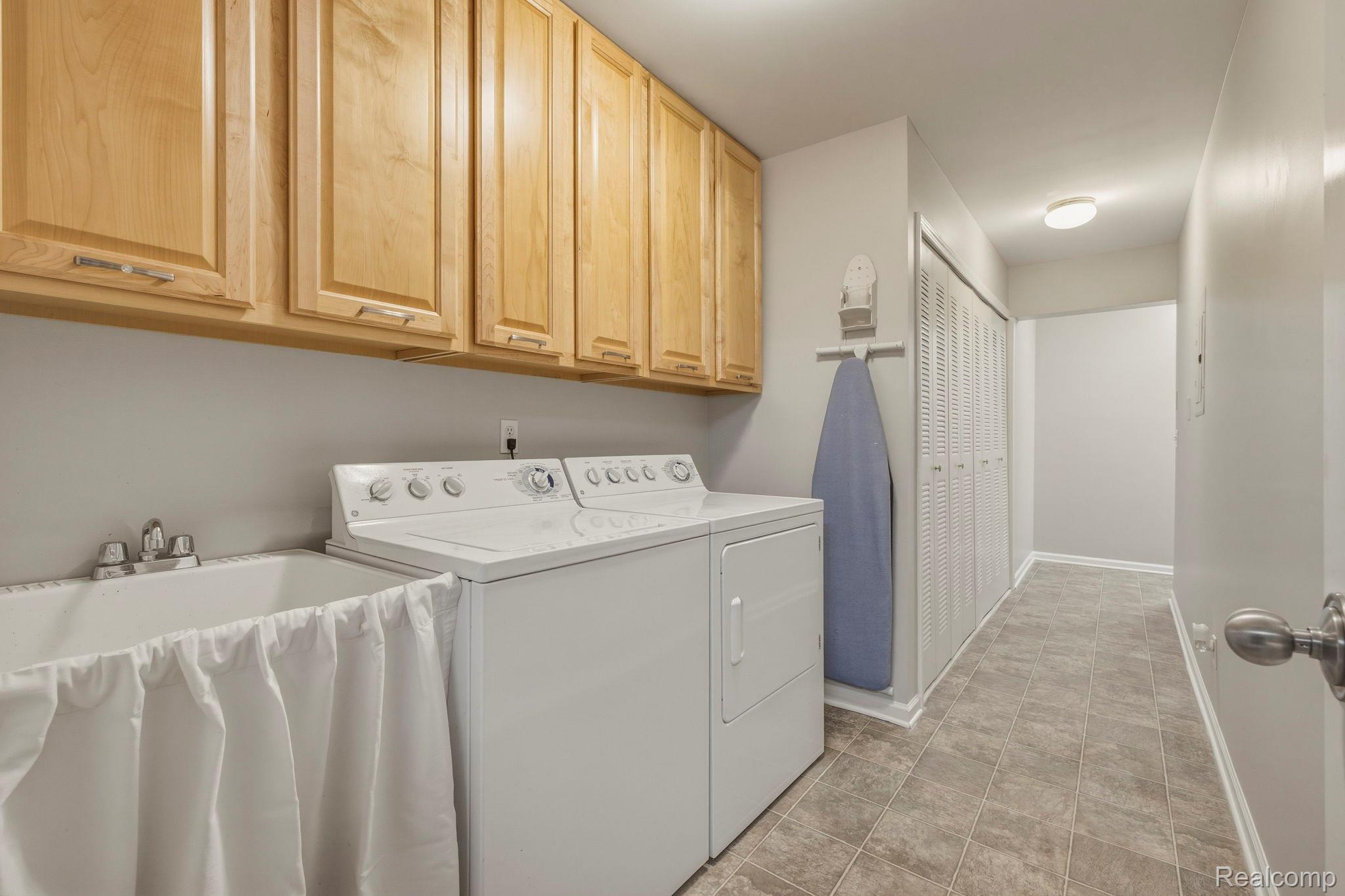1905 Flagstone Circle Rochester, MI 48307 - Photo 28 of 33 Laundry area featuring extensive wood cabinetry, a utility sink, and tile flooring