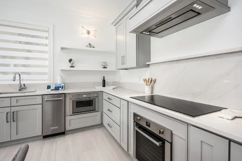 a kitchen with stainless steel appliances granite countertop a sink a stove a refrigerator and island with wooden floor