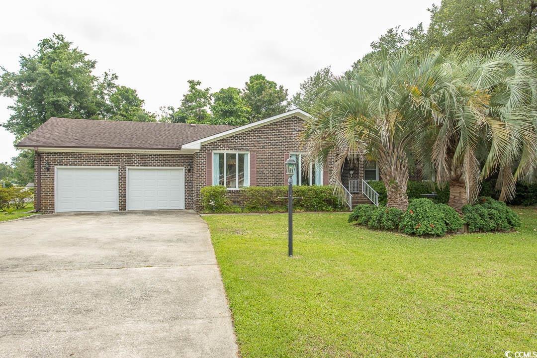 View of front of home featuring an attached garage, driveway, a front yard, and brick siding
