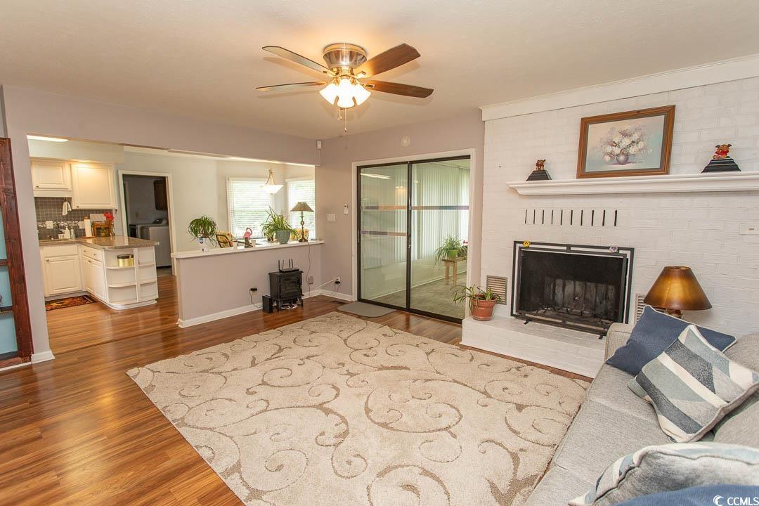 18 Pine Valley Lane Surfside Beach, SC 29575 - Photo 12 of 35 Living area with wood finished floors, a ceiling fan, and a brick fireplace