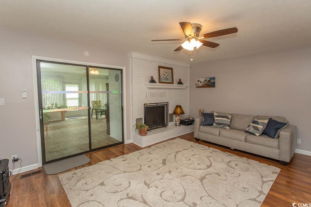 18 Pine Valley Lane Surfside Beach, SC 29575 - Photo 14 of 35 Living room with a ceiling fan, wood finished floors, baseboards, and a brick fireplace
