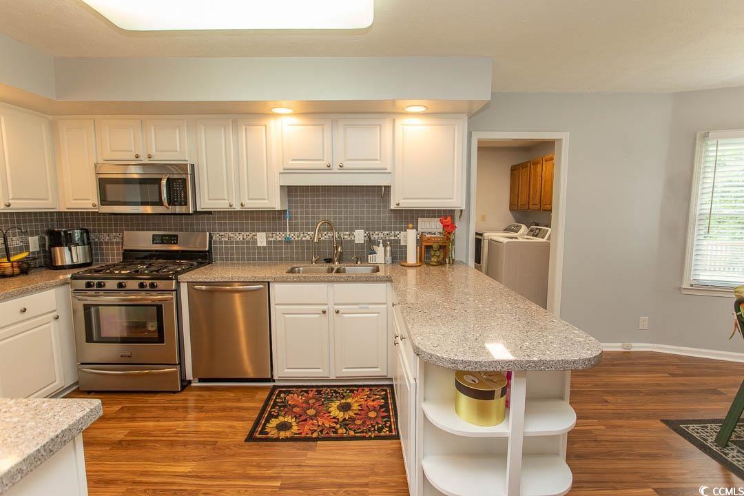 18 Pine Valley Lane Surfside Beach, SC 29575 - Photo 4 of 35 Kitchen with appliances with stainless steel finishes, a sink, washing machine and clothes dryer, open shelves, and white cabinets