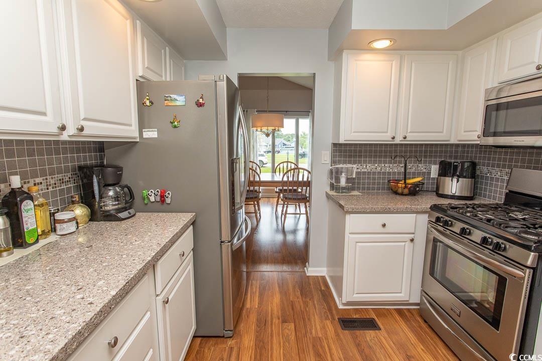 18 Pine Valley Lane Surfside Beach, SC 29575 - Photo 6 of 35 Kitchen with stainless steel appliances, light wood finished floors, white cabinets, and decorative backsplash