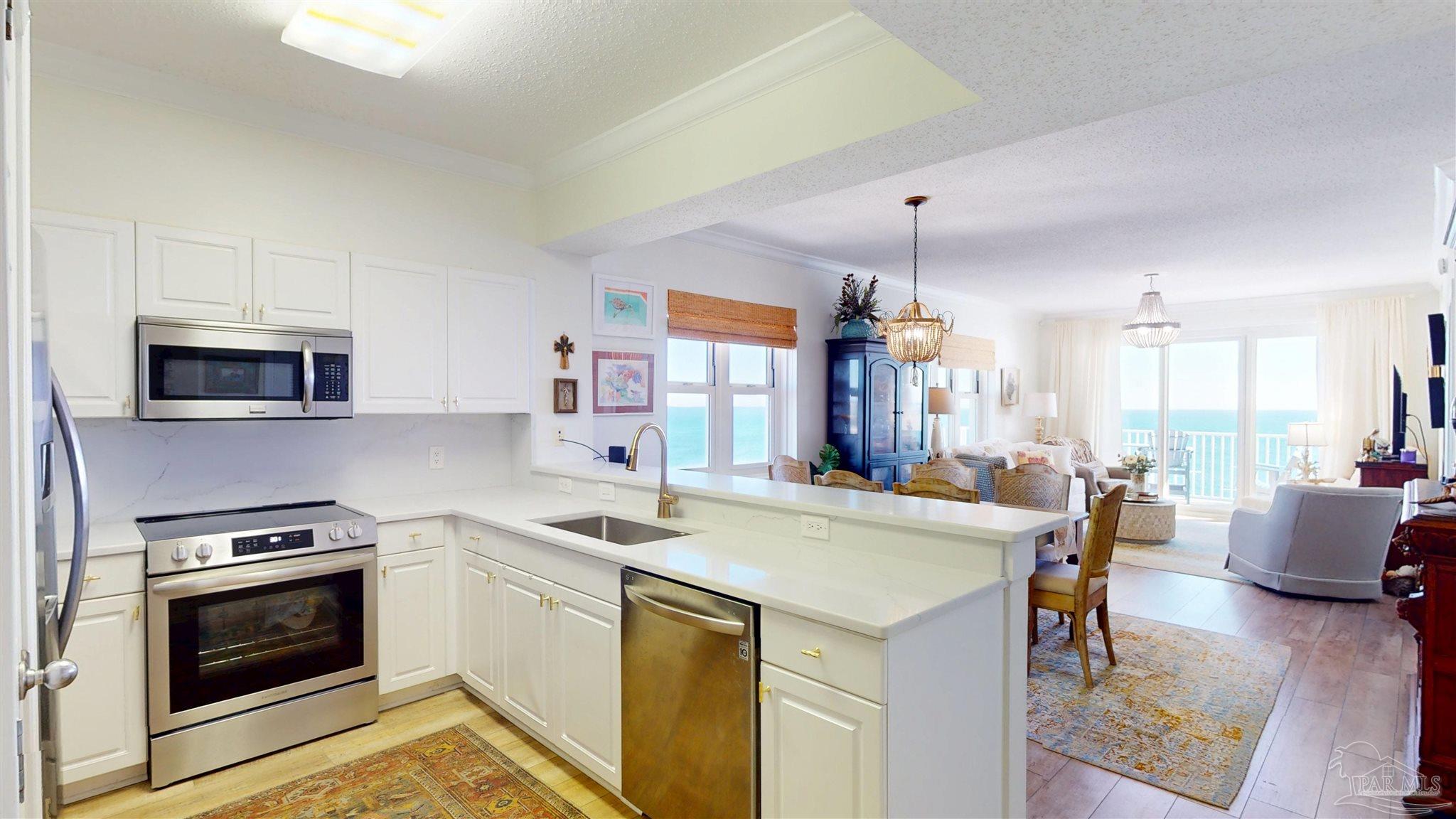 14511 Perdido Key Drive, Unit 1301 Perdido Key, FL 32507 - Photo 3 of 65 a kitchen that has a stove a microwave a dining table and chairs with wooden floor