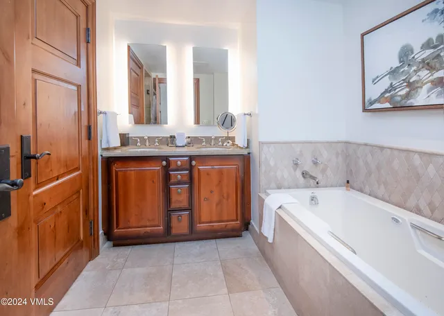 a spacious bathroom with a tub sink and mirror