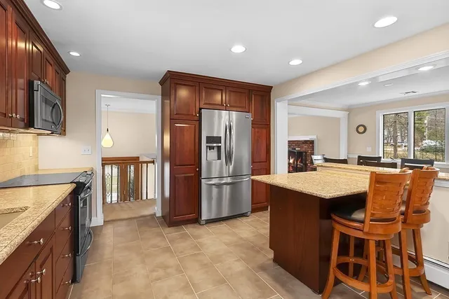 a kitchen with stainless steel appliances granite countertop a refrigerator a stove a sink a microwave and island