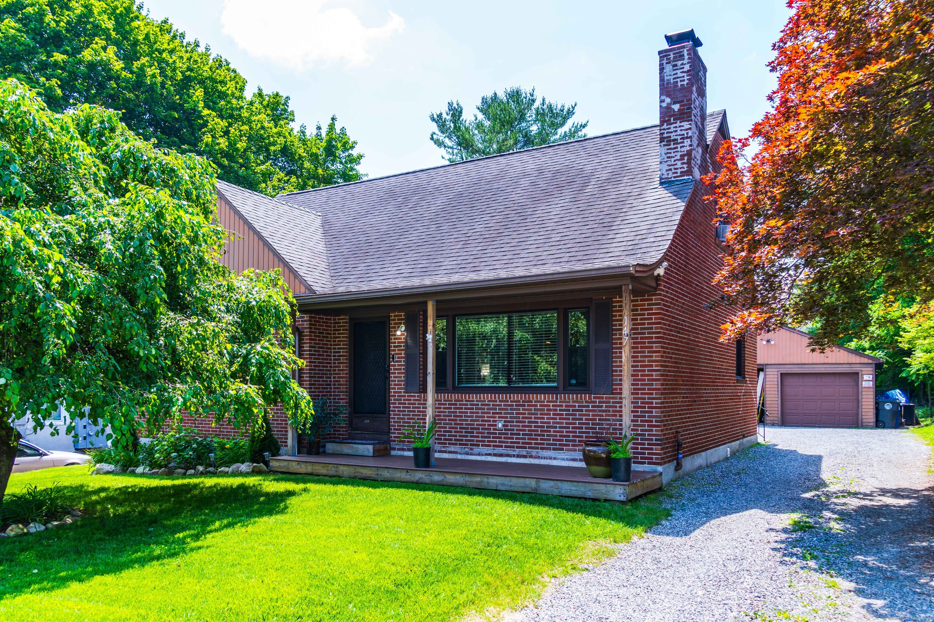a view of a house with a yard potted plants and a large tree