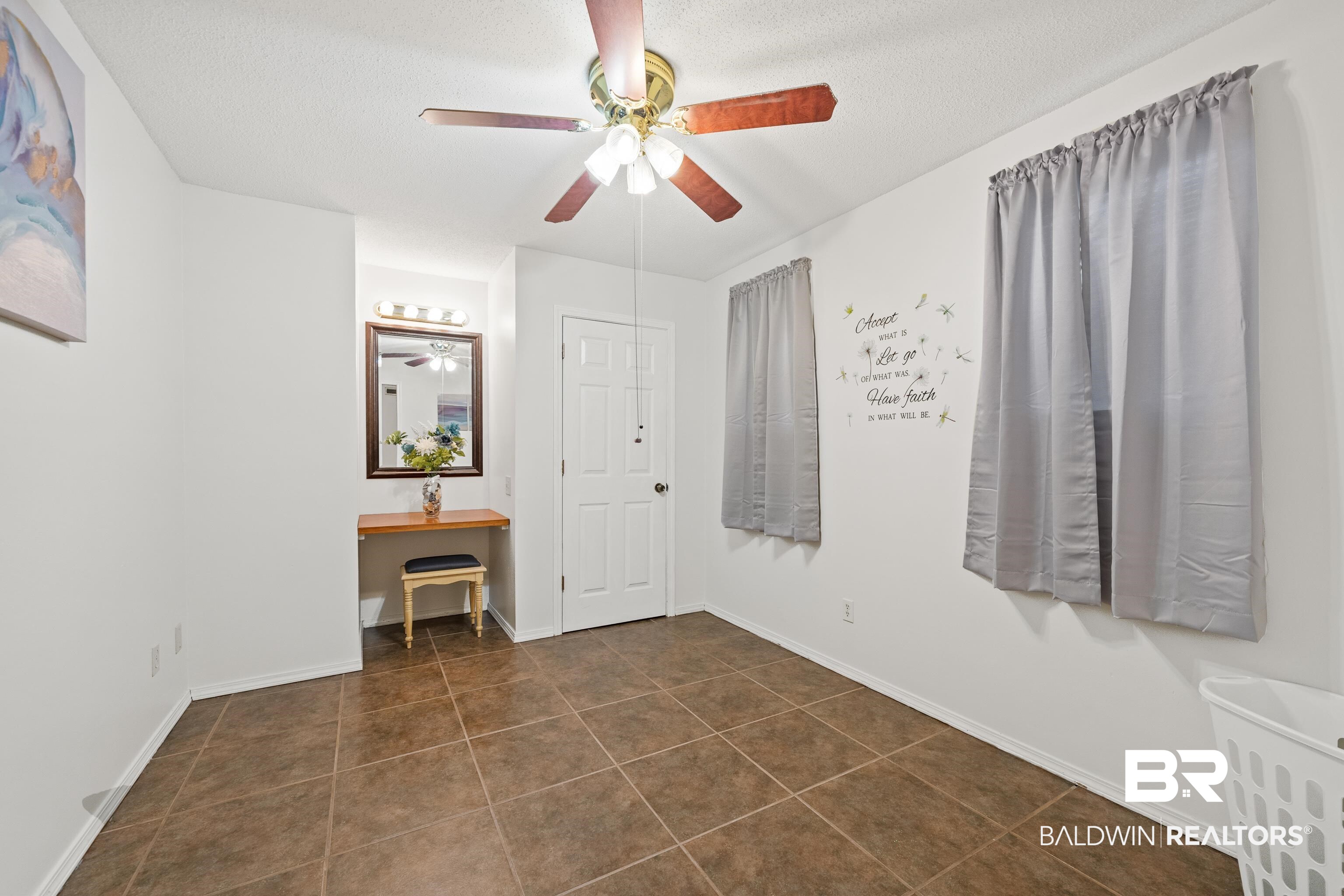 460 Ridgewood Drive Daphne, AL 36526 - Photo 10 of 31 Unfurnished bedroom featuring a textured ceiling, ceiling fan, and dark tile patterned flooring