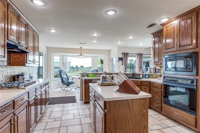 a view of a kitchen with kitchen island wooden cabinets and stainless steel appliances
