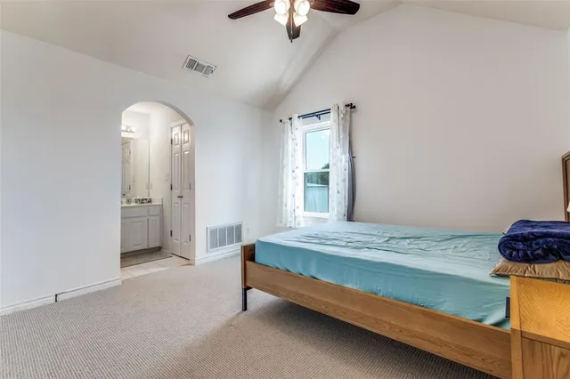 a spacious bedroom with a bed and a chandelier fan