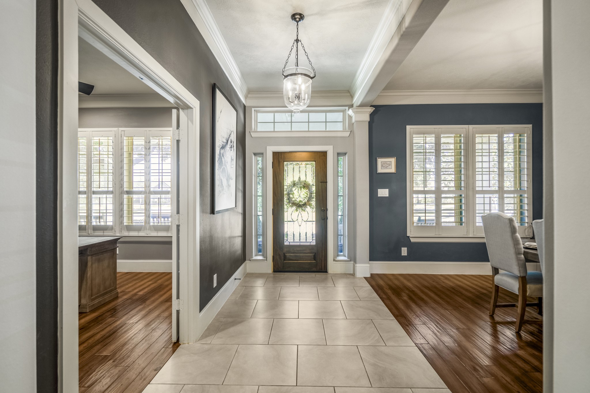 3710 Snowden Point Lane Spring, TX 77386 - Photo 9 of 50 This elegant entryway features a welcoming glass-paneled front door with sidelights, abundant natural light from large windows with shutters, and a stylish mix of tile and wood flooring. The space is enhanced by crown molding, a modern light fixture, and opens to a dining area on the right with the office on the left.