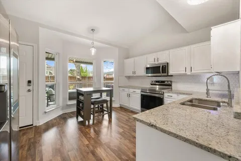 a kitchen with granite countertop white cabinets and stainless steel appliances