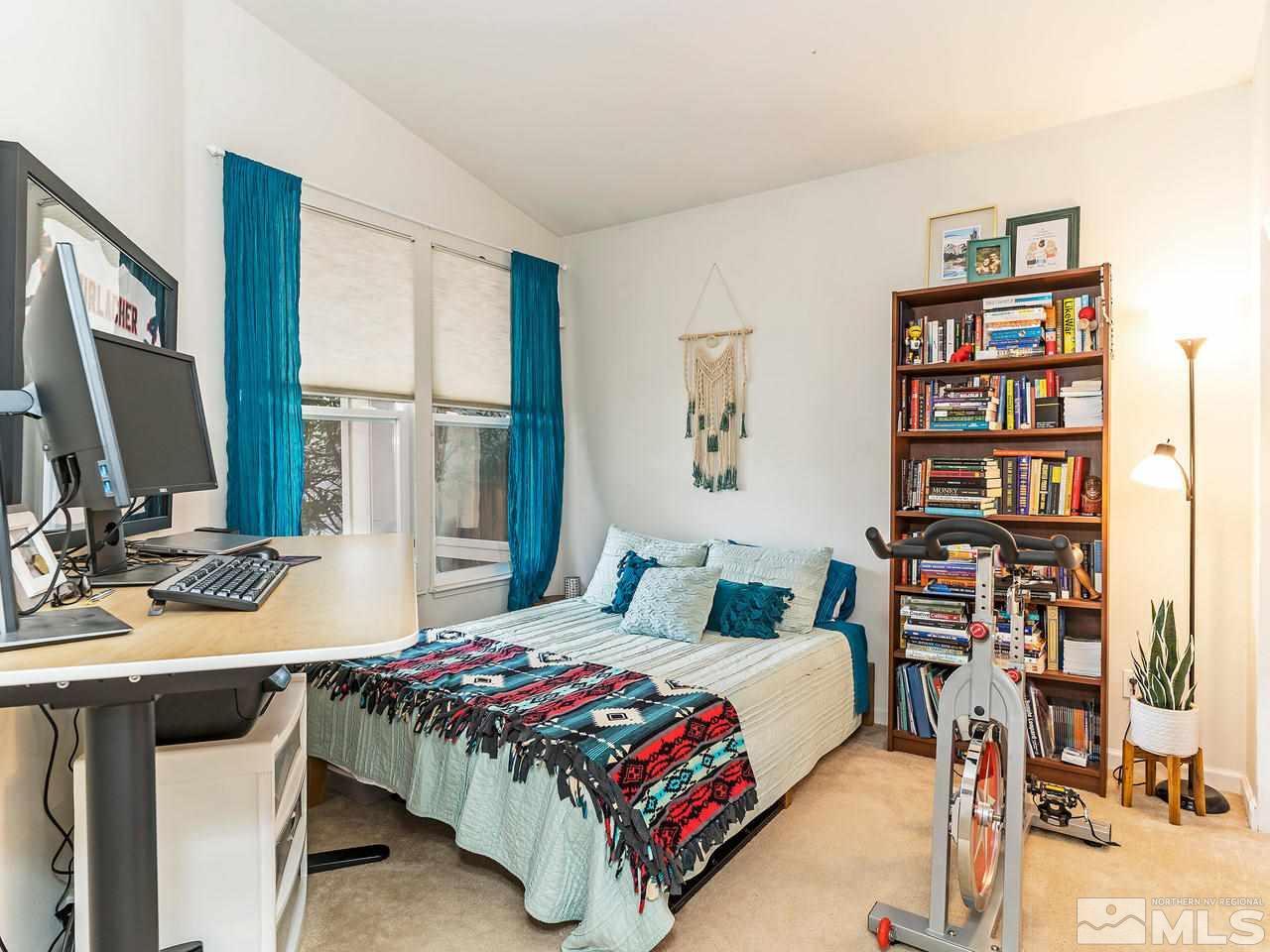 875 Caughlin Crossing Reno, NV 89519 - Photo 13 of 21 a bedroom with a large bed a book shelf and a window