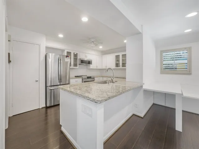 a large kitchen with a center island wooden floor and stainless steel appliances