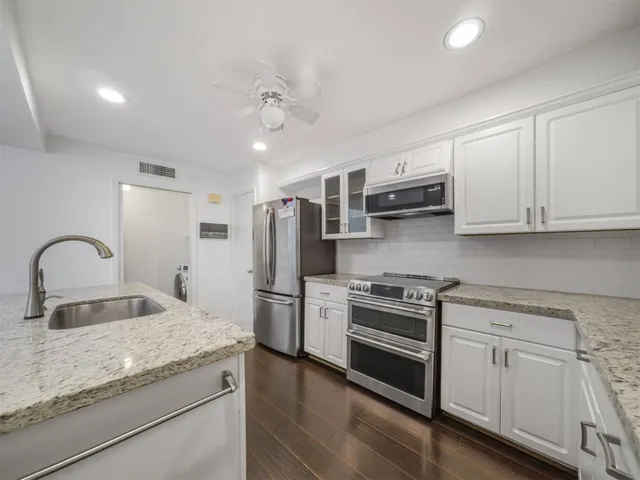 a kitchen with stainless steel appliances granite countertop a refrigerator sink and stove