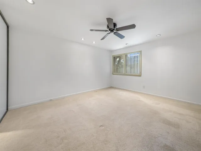 a view of a big room with a ceiling fan and windows
