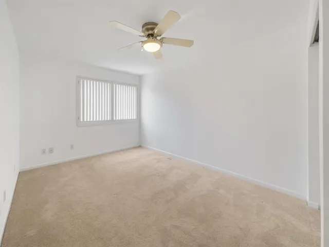 an empty room with windows fan and fan