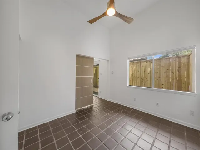 an empty room with windows and fan