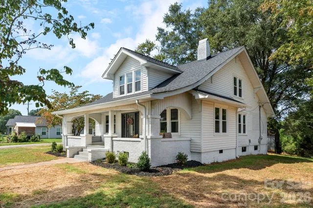 a view of a white house with a big yard and large trees