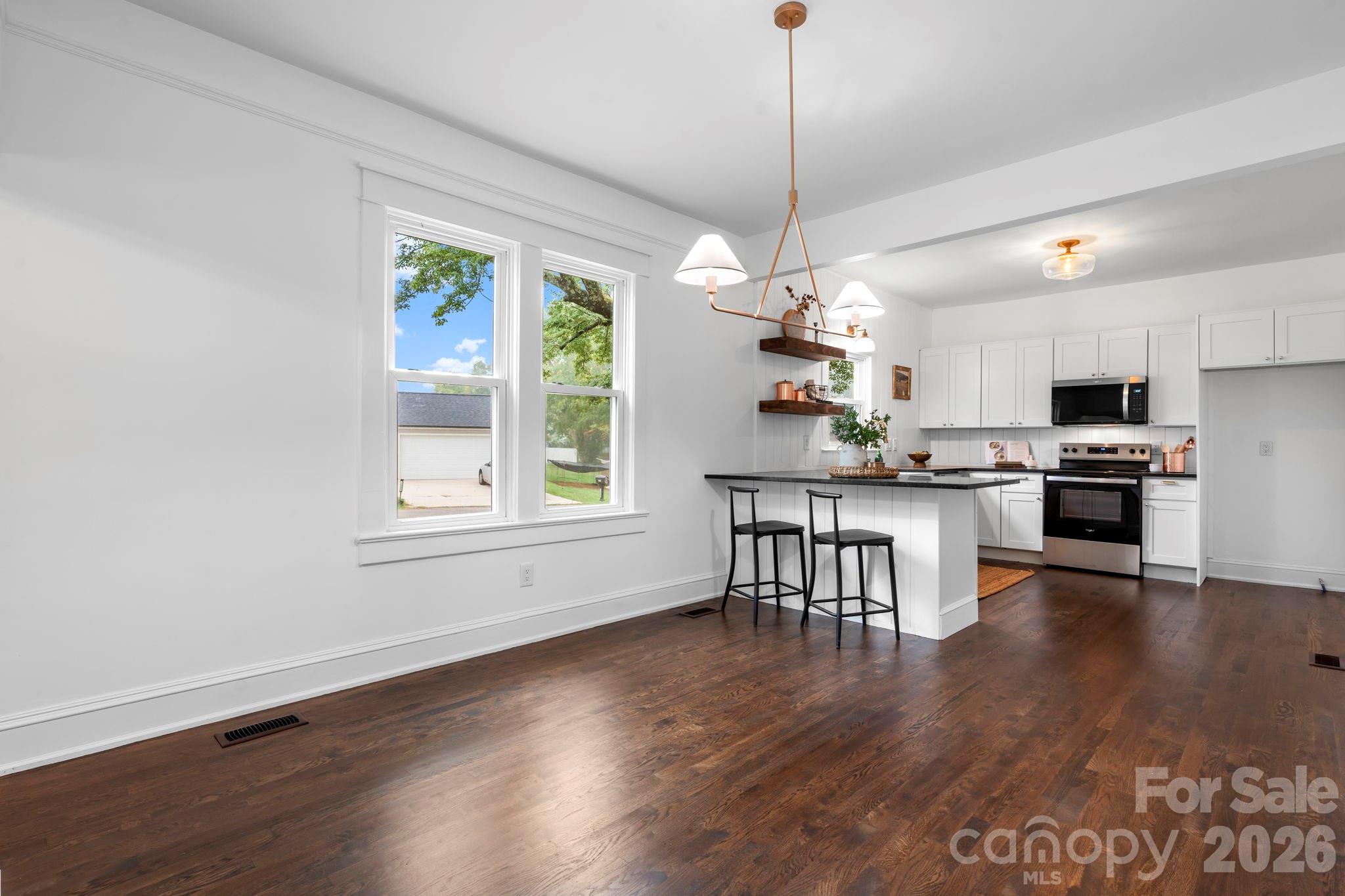 1590 South Center Street Hickory, NC 28602 - Photo 8 of 29 a open kitchen with stainless steel appliances granite countertop a stove top oven a dining table and chairs with wooden floor