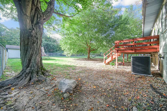 a backyard of a house with wooden floor and large trees