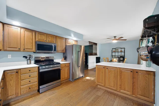 a kitchen with stainless steel appliances granite countertop a refrigerator oven a sink dishwasher and white cabinets with wooden floor