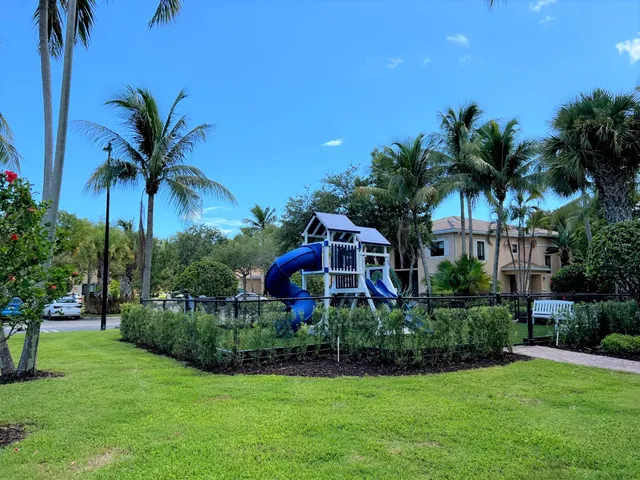a view of a house with a yard and palm trees