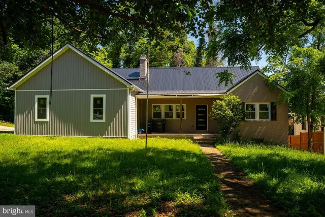 a front view of a house with a garden and trees
