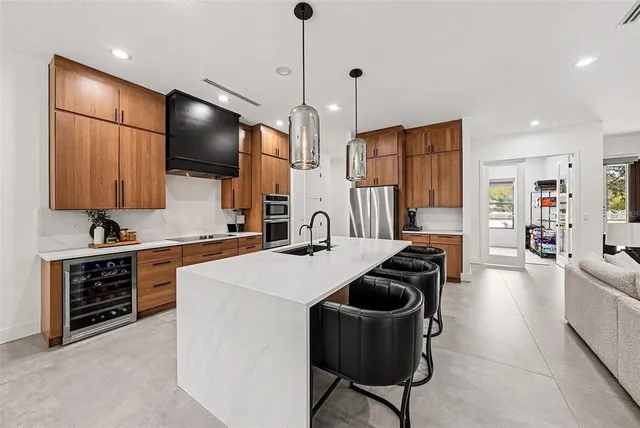 a kitchen with stainless steel appliances granite countertop a sink a stove a refrigerator and island with wooden floor